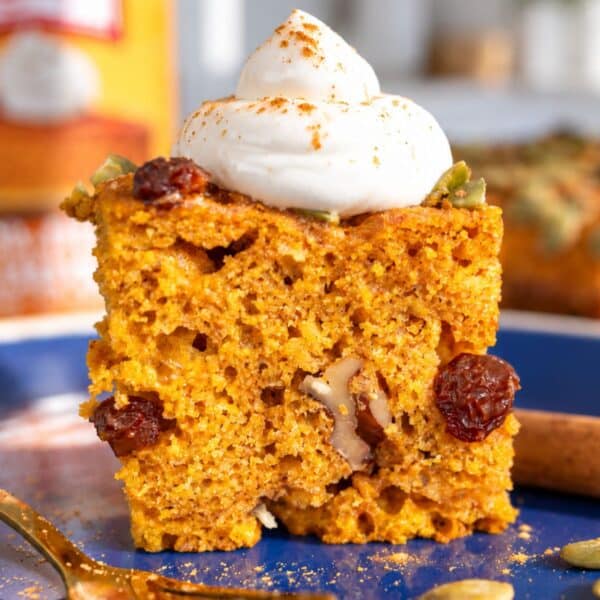 Greek yogurt pumpkin cake square topped with yogurt and pumpkin seeds.