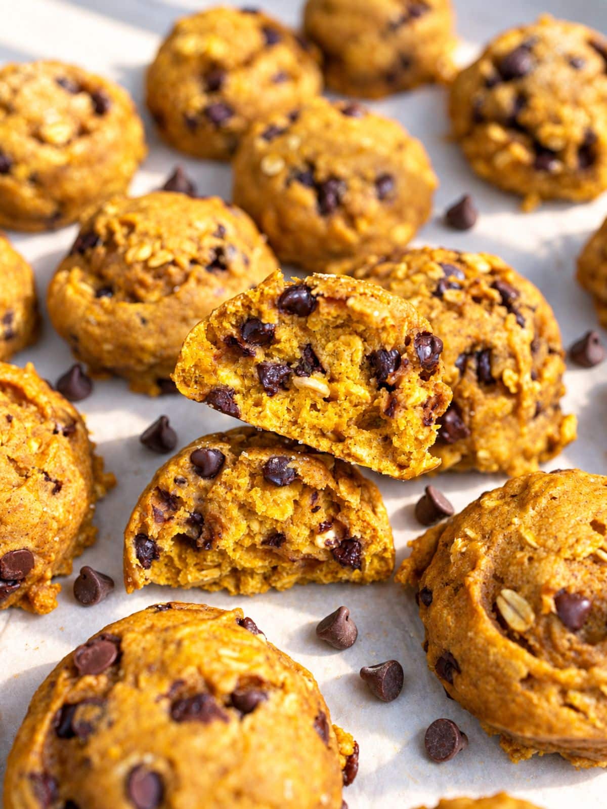 Halved pumpkin cookie revealing a soft center with oats and chocolate chips.