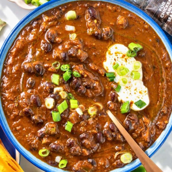 Hearty Cajun black bean soup in a bowl with lime wedges nearby.