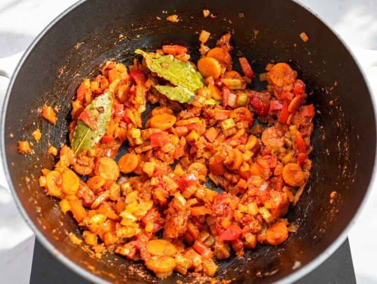 Step 2 Garlic, tomato paste, bay leaves, oregano, and pepper flakes coating softened vegetables.
