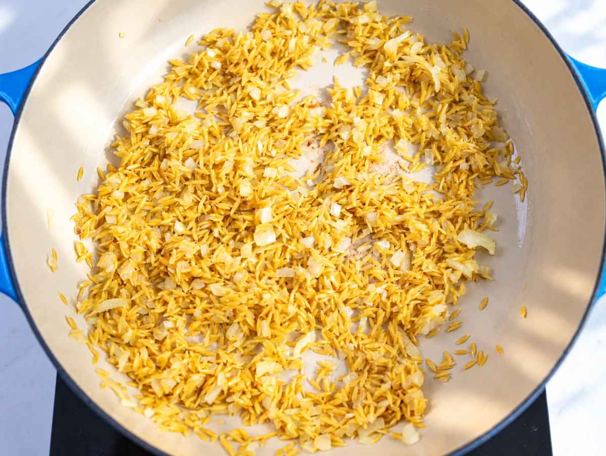 Step 2 Uncooked orzo and grated garlic stirred into softened onions.
