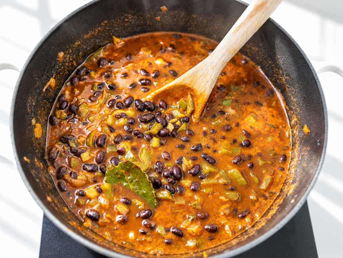 Step 3 Black beans simmering in seasoned broth with vegetables and bay leaf.