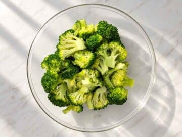 Step 3 Bright green steamed broccoli florets in a bowl.