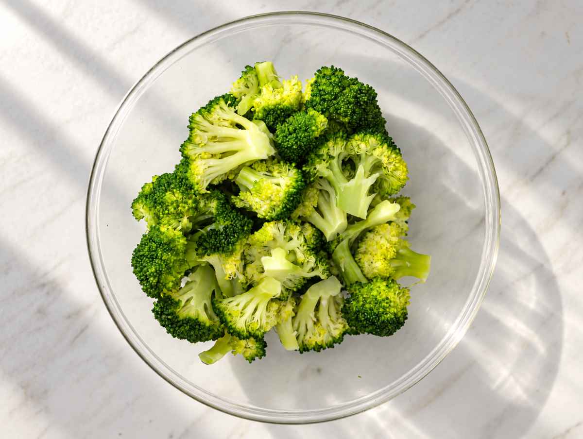 Step 3 Bright green steamed broccoli florets in a bowl.