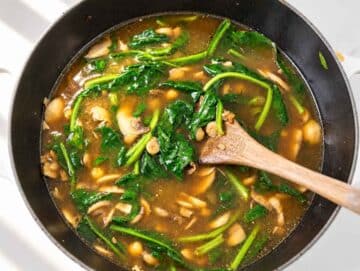 Step 3 Fresh spinach wilting into chickpea soup with mushrooms.