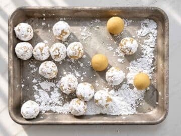 Step 3 Small cookie dough balls coated in powdered sugar on a baking sheet.