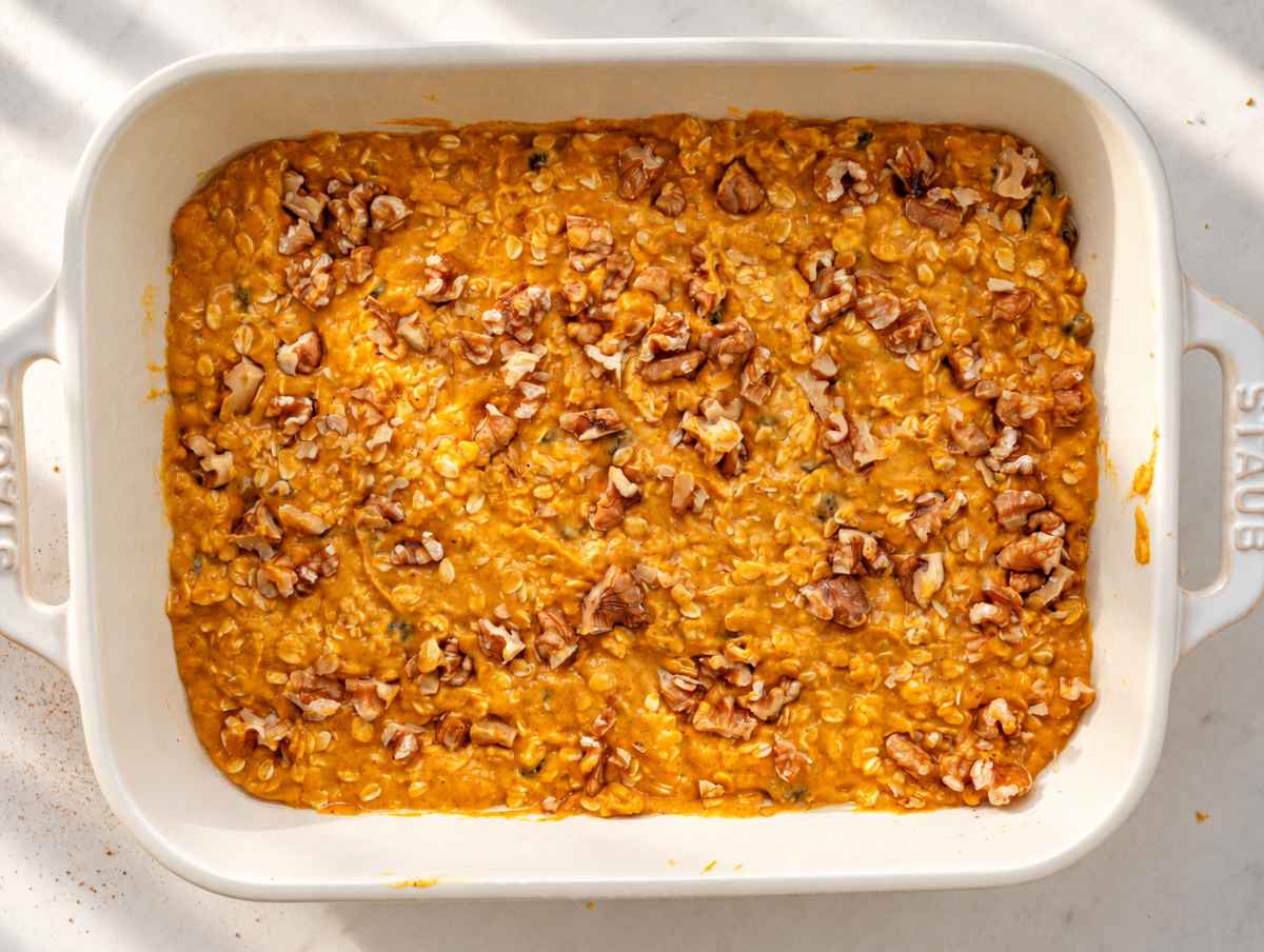 Step 3 Unbaked pumpkin oatmeal topped with chopped walnuts in a white dish.