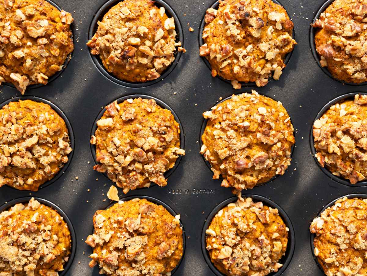 Step 4 Baked muffins with golden walnut tops cooling in a muffin pan.