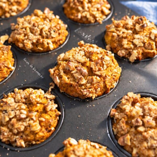 Walnut-topped pumpkin oatmeal muffins cooling in daylight.